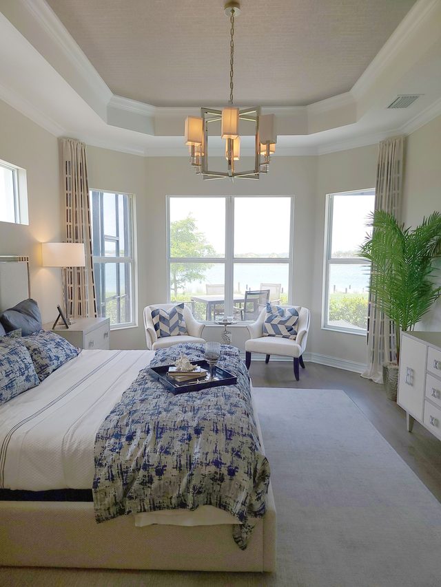 Bright blue-and-white coastal bedroom with a subtle woven grasscloth wallcovering and a bay window.